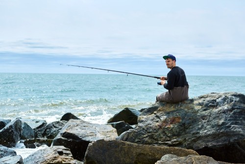 young-man-sitting-on-rock-sea-fishing.jpg